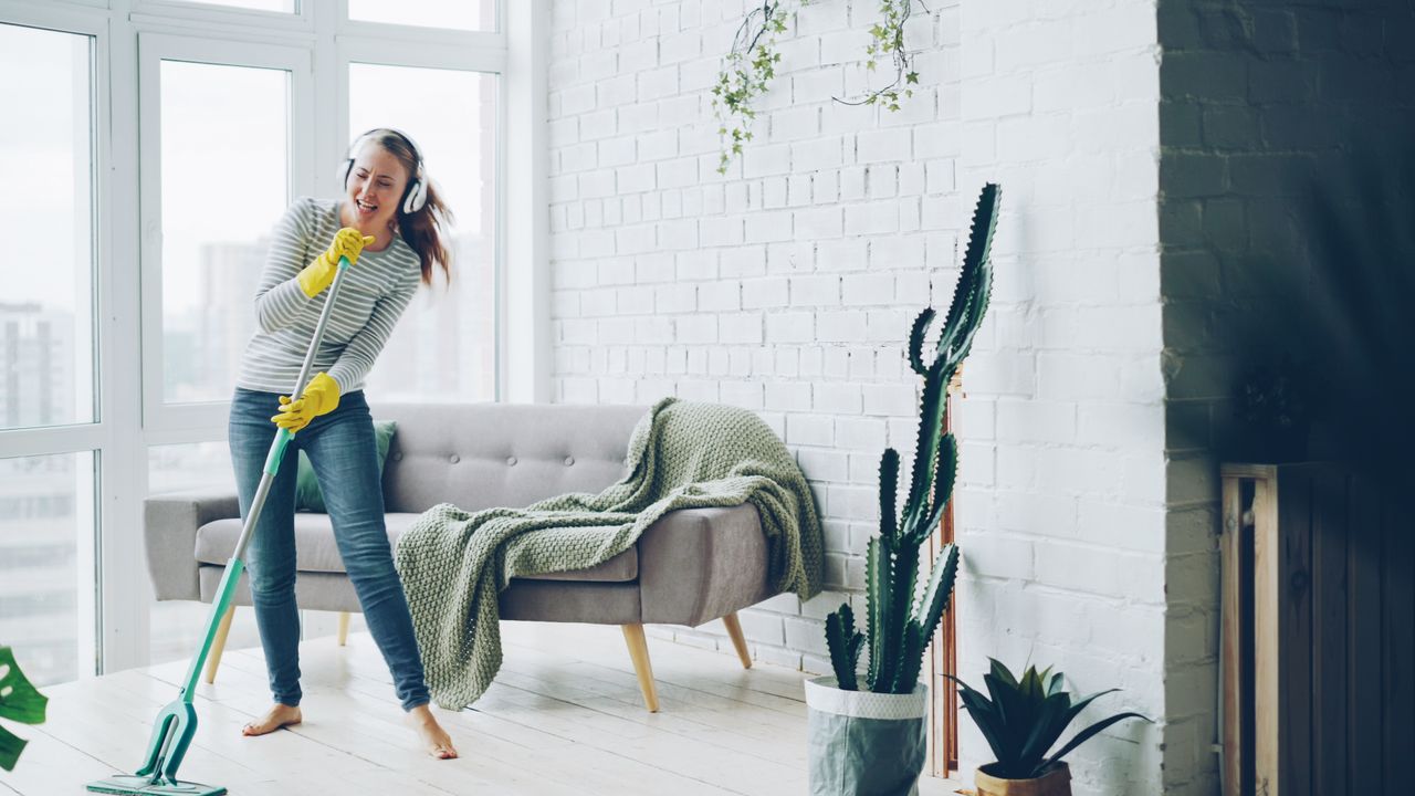 about-04 Happy woman listening to music while mopping a modern living room.